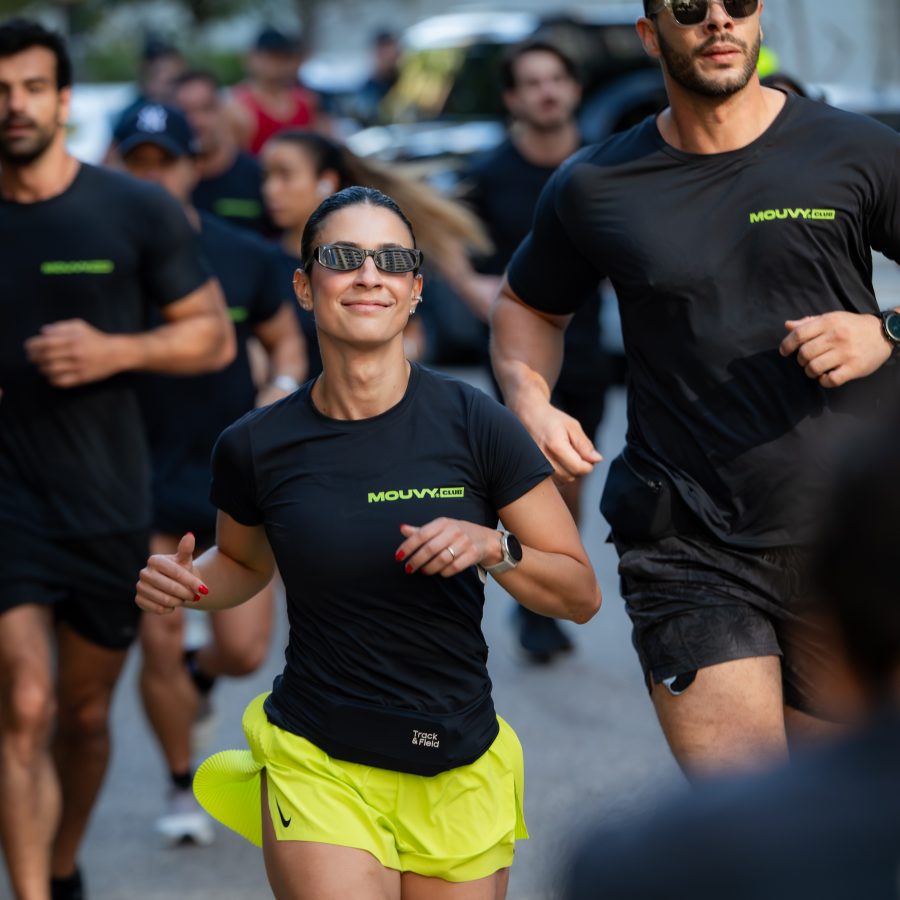 Atleta do Mouvy Club correndo em treino de rua, cercada pelo grupo